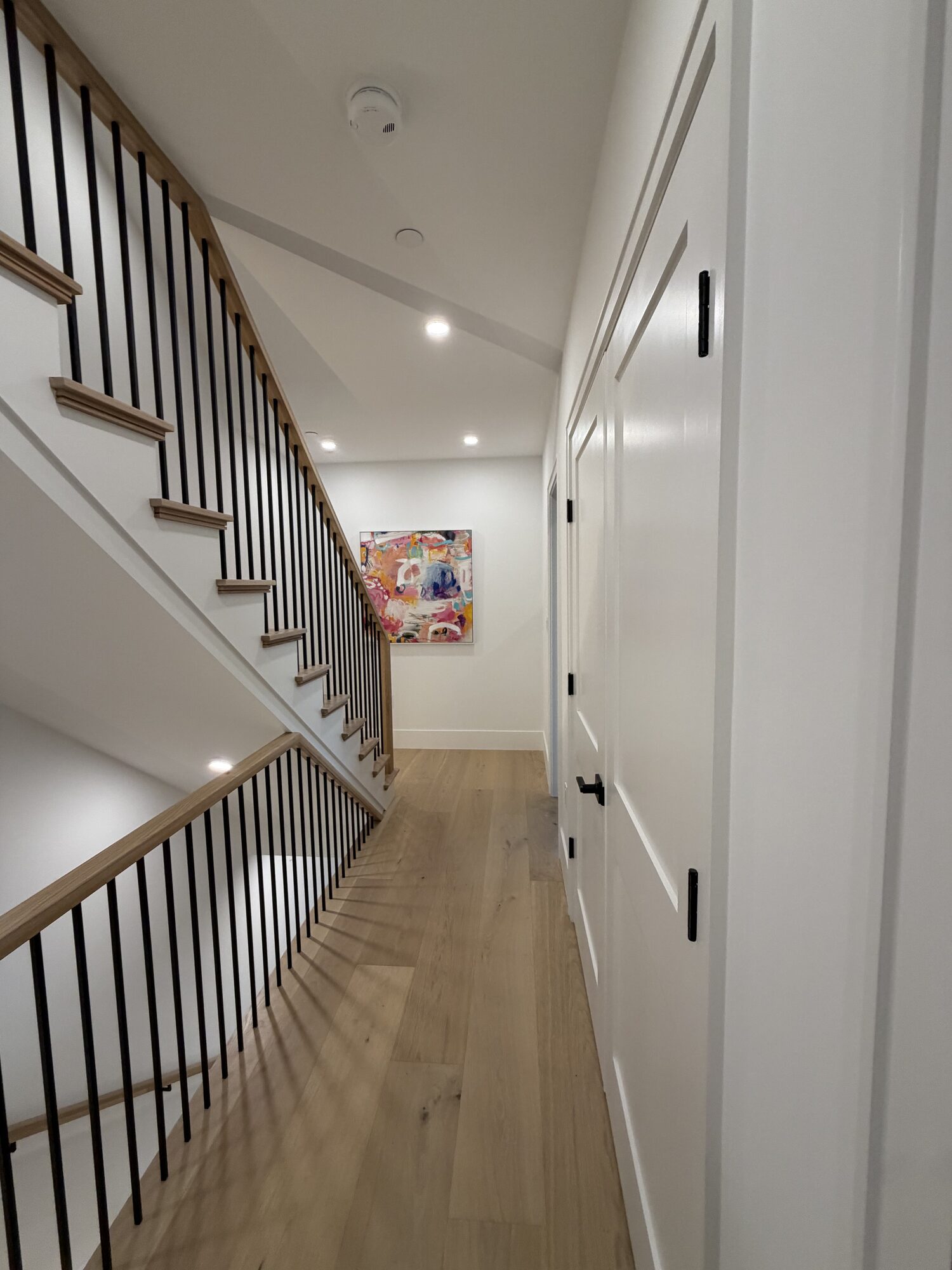 Finished hallway and stair with hung abstract artwork at the landing at 421 East Sixth Street, Residence 4, South Boston