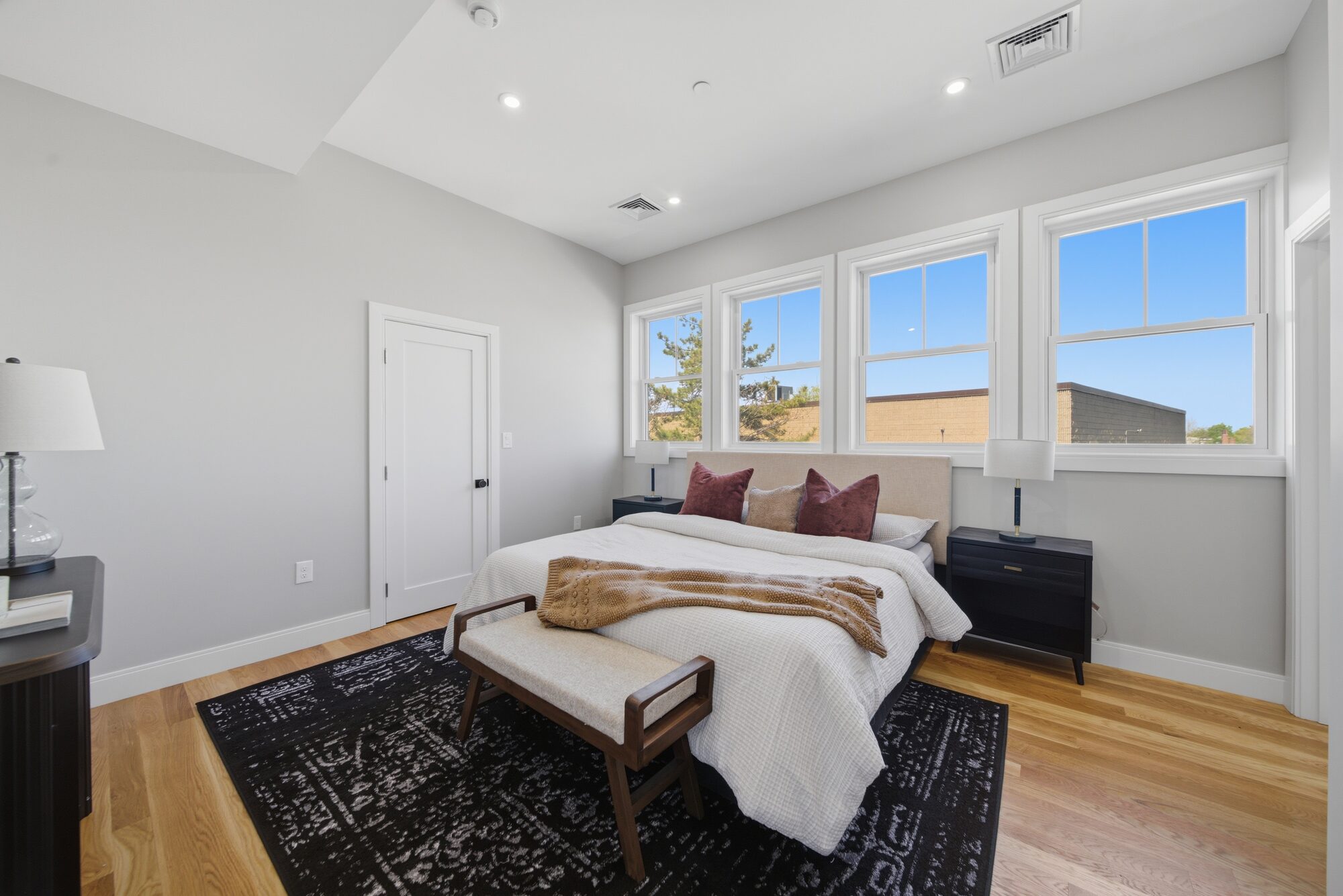 Primary bedroom with bed, four windows, and hardwood floors at 174 Walnut Street, Unit 3