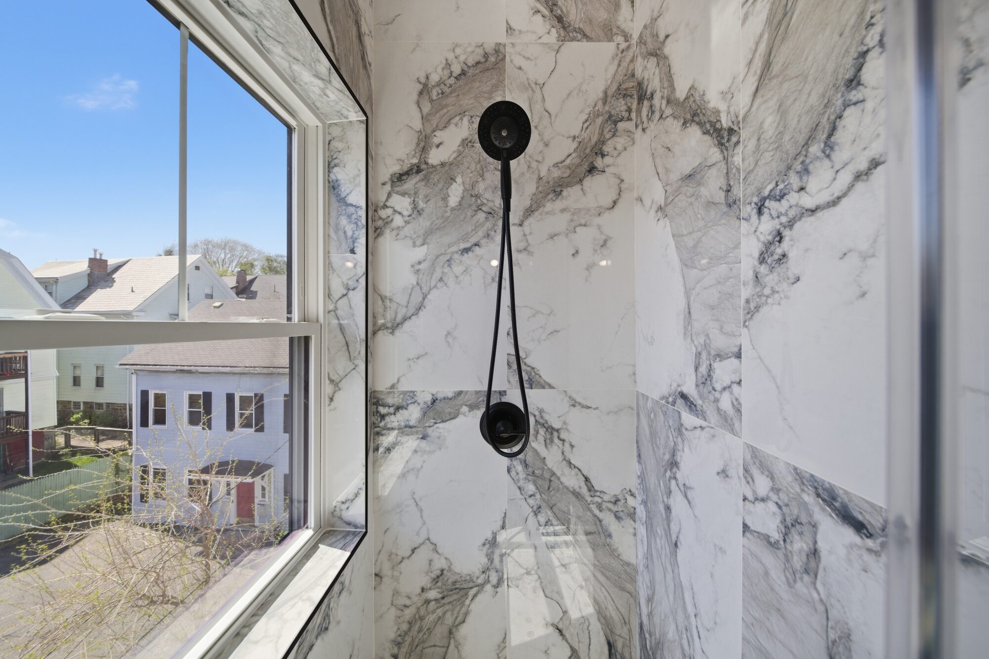Shower detail with marble tile, matte black fixture, and window at 174 Walnut Street, Unit 3